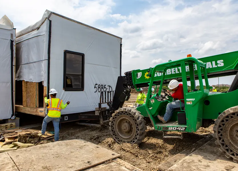 Forklift moving modular building module into place